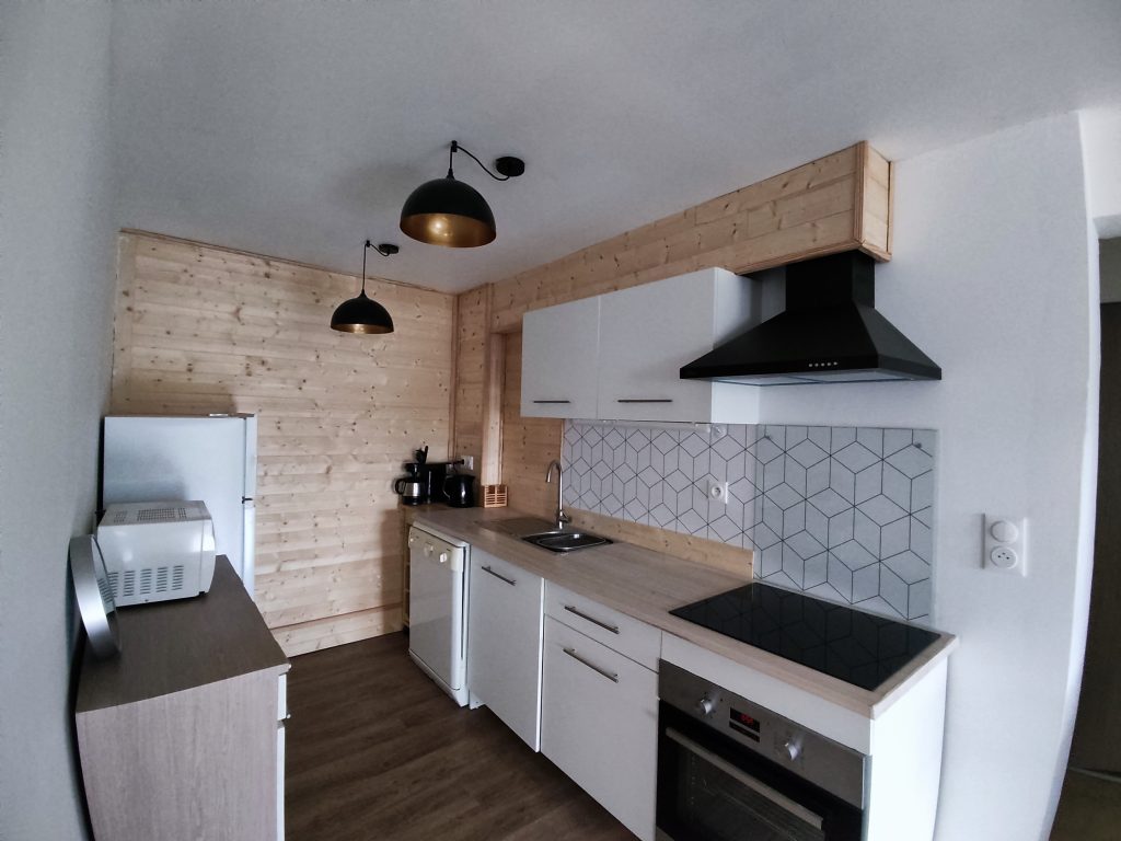 Cuisine moderne avec bois clair, carrelage graphique et éclairage suspendu – DécoByPat